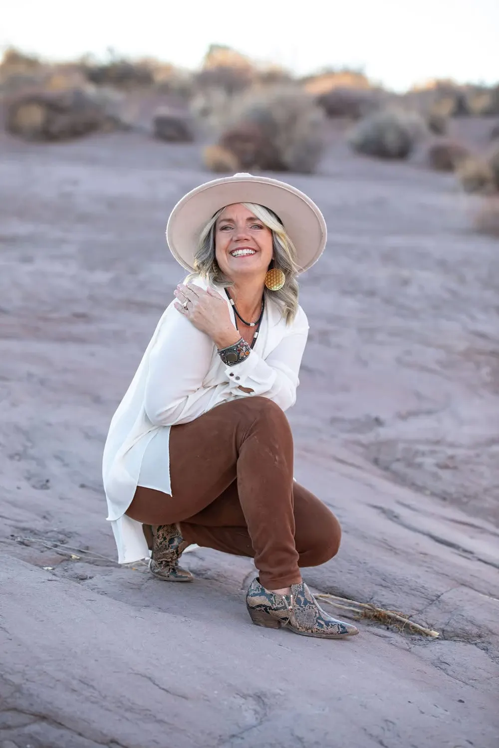 Wendy Bunnell, smiling, in a wide-brimmed hat among desert rocks
